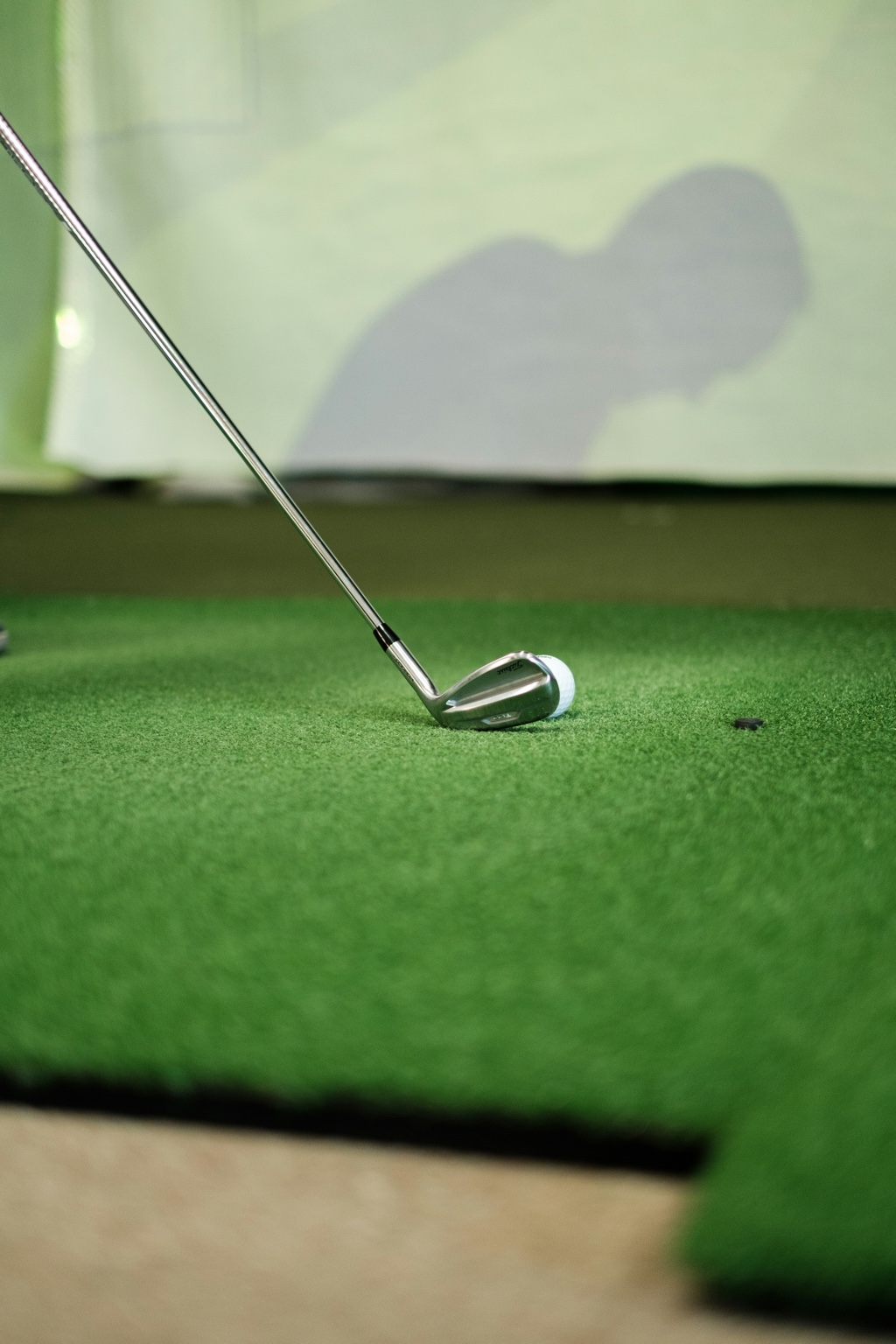 Golf club and ball on indoor turf in a budget-friendly simulator setup